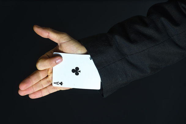 Man with ace up his sleeve on black background - Photo, Image