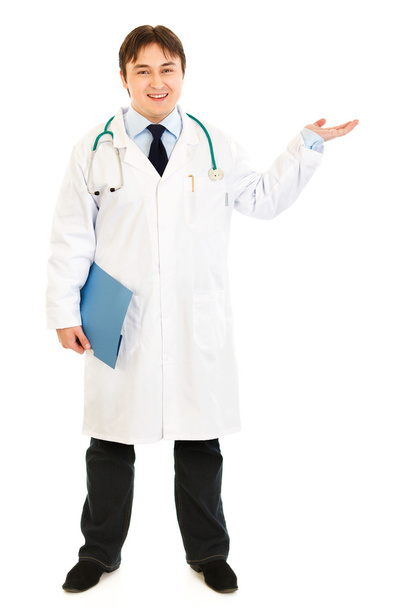Full length portrait of doctor holding medical chart and presenting somethi - Φωτογραφία, εικόνα