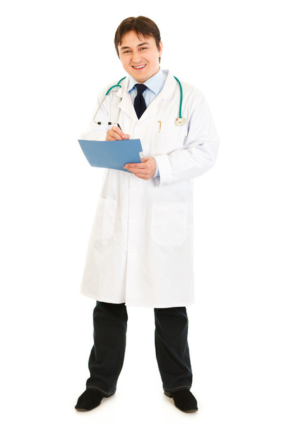 Smiling medical doctor making notes in medical chart - Photo, image