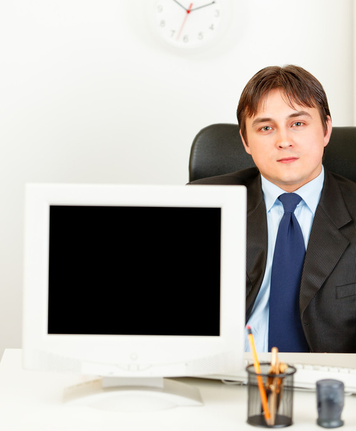 Modern businessman sitting at office desk and showing monitors blank screen - Zdjęcie, obraz