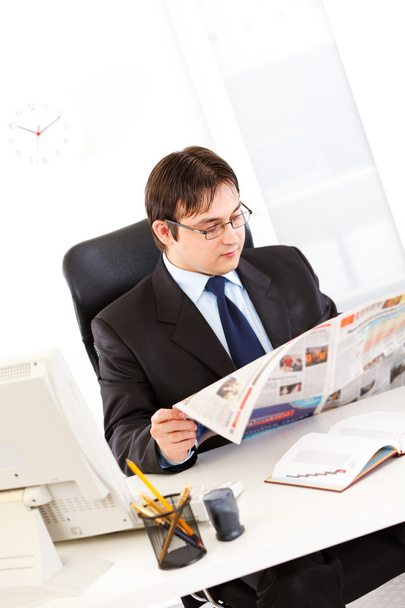 Uomo d'affari moderno seduto alla scrivania dell'ufficio e leggendo il giornale
 - Foto, immagini