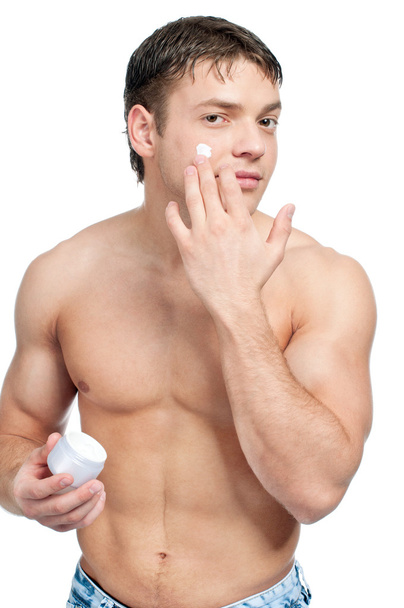 Man putting on cream lotion on face - Foto, afbeelding