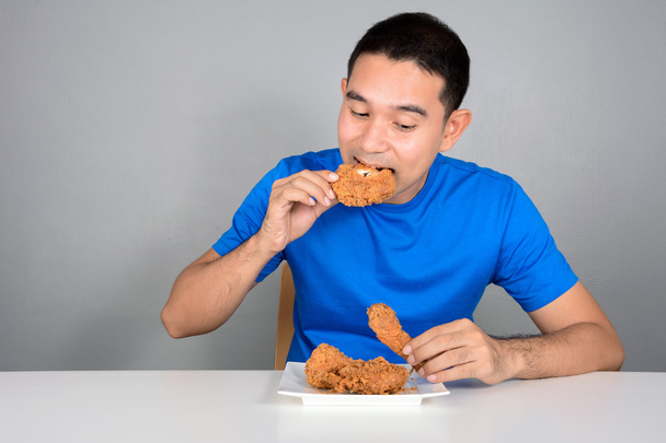 Jeune homme mordant poulet frit
 - Photo, image