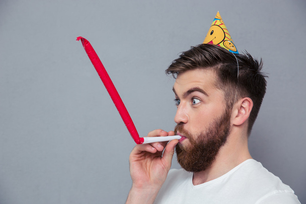 Man with party hat blowing in whistle - Foto, afbeelding