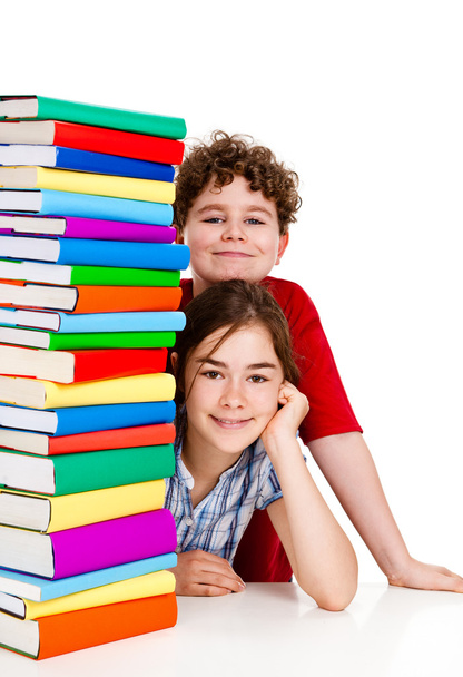 Students sitting behind pile of books on white - Foto, Imagen