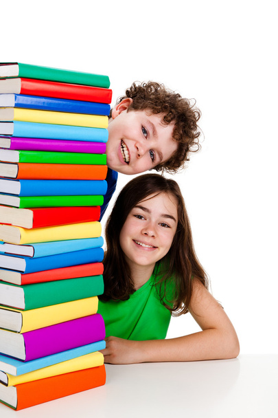 Students sitting behind pile of books on white - Фото, изображение
