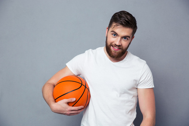 Happy casual man holding basket ball - Foto, afbeelding