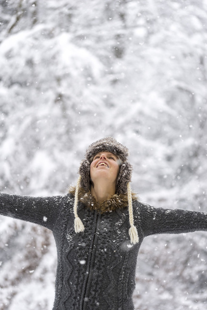 Молодая женщина, празднующая зиму, широко раскинула руки
 - Фото, изображение