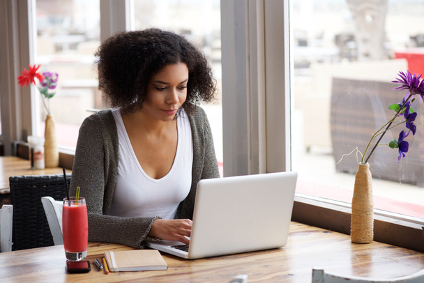 African american young woman sitting at cafe with laptop - 写真・画像