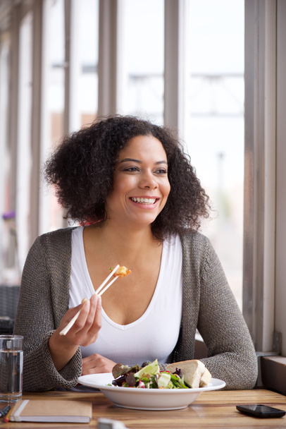 Afrikai-amerikai fiatal nő ül kávézóban eszik saláta - Fotó, kép