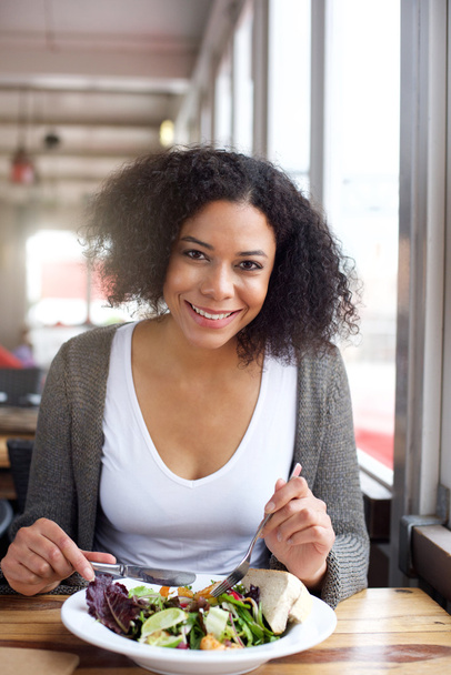 Smiling black woman eating salad at restaurant - Foto, afbeelding