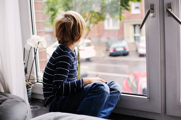 bambino seduto vicino alla finestra
 - Foto, immagini