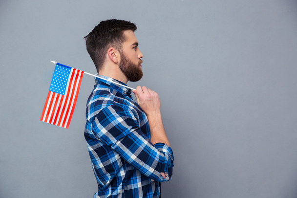 Side view portrait of a casual man holding USA flag - Zdjęcie, obraz