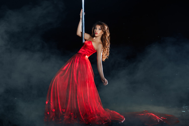 Lány piros ruhában táncol körül egy pole éjszaka köd. - Fotó, kép