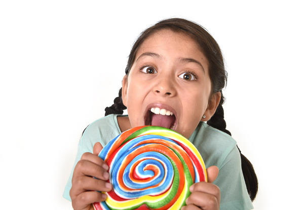 happy female child holding big lollipop licking the candy with her tongue in kids love candy concept - Fotografie, Obrázek