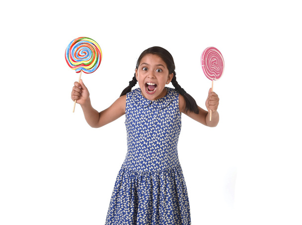 happy female child holding two big lollipop in crazy funny face expression in sugar addiction - Zdjęcie, obraz