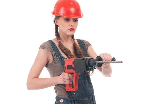 Young playful woman in jeans coverall holding perforator drill - Foto, afbeelding