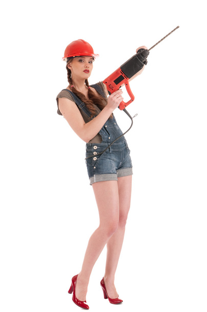 Young playful woman in jeans coverall holding perforator drill - Foto, Bild