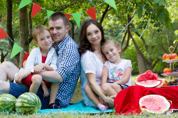Сім'я з двома дітьми на пікніку з кавуна
 - Фото, зображення