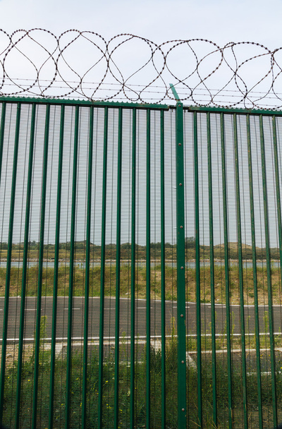 Зеленый забор с колючей проволокой охраняет французский паромный терминал
. - Фото, изображение