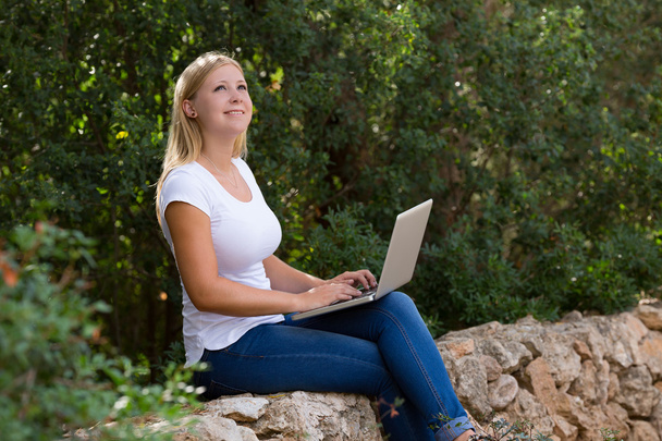 Молода жінка використовує ноутбук на відкритому повітрі
 - Фото, зображення