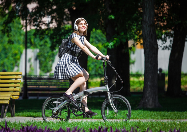 Young woman rides bicycle in the park - Zdjęcie, obraz