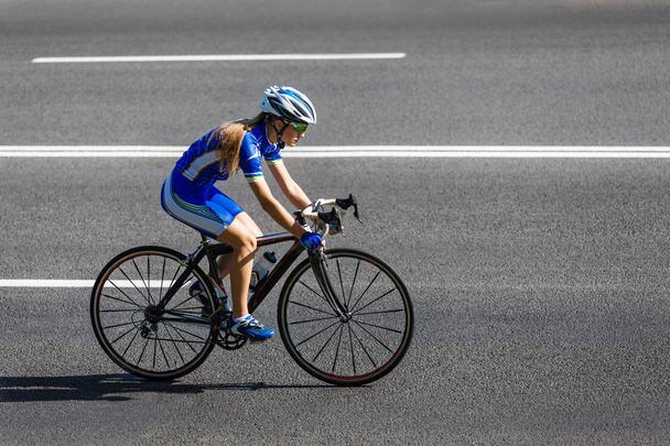 Ciclista fêmea monta uma bicicleta de corrida na estrada
 - Foto, Imagem