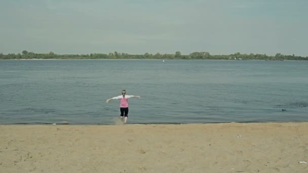 girl joyfully running near the water on the dirty beach - Felvétel, videó