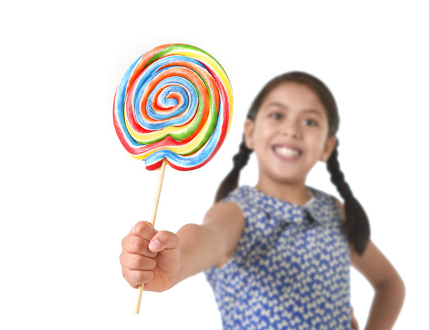 Latin female child holding huge lollipop happy and excited in cute blue dress and pony tails candy concept - Photo, Image