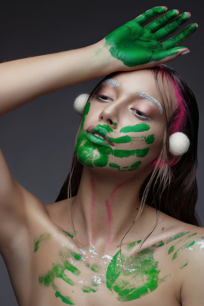 schöne junge Frau mit sauberer frischer Haut rosa Make-up und Handabdruck mit grüner Farbe - Foto, Bild