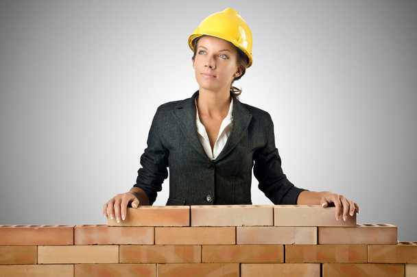 Jovem construtor feminino perto da parede de tijolo
 - Foto, Imagem