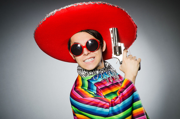 Mann im hellen mexikanischen Poncho hält Handfeuerwaffe gegen Grau - Foto, Bild