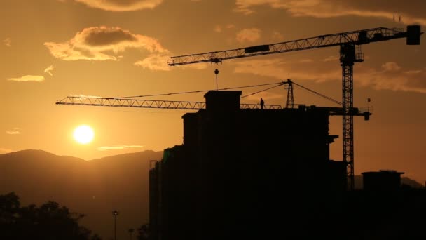silhouet kraan werken in bouwplaats en zonsondergang - Video