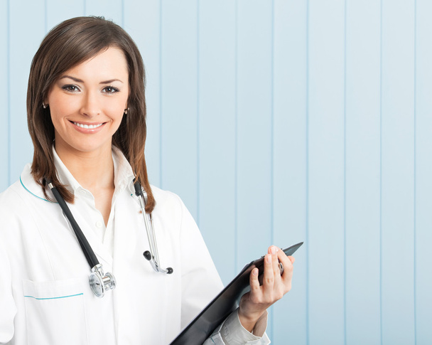 Smiling female doctor with clipboard at office - Foto, immagini