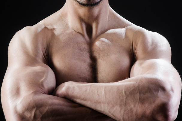 Muskulöser Mann posiert im dunklen Studio - Foto, Bild