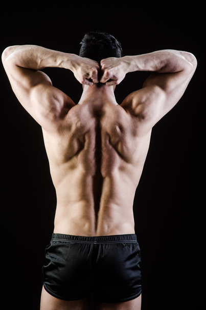 Muscular man posing in dark studio - Photo, image