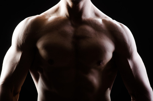 Musclé homme posant dans sombre studio - Photo, image