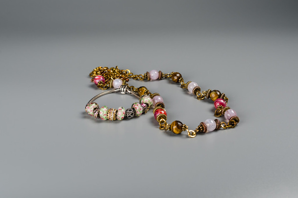 Perles multicolores et bracelet avec breloques sur un fond gris
 - Photo, image