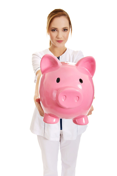 Female doctor holding a piggybank. - Фото, зображення