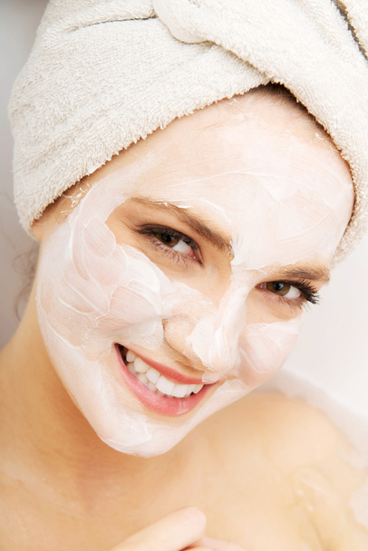 Woman relaxing in bathtub with face mask. - Foto, Bild