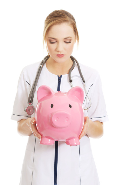 Doctor holding a piggybank. - Фото, изображение