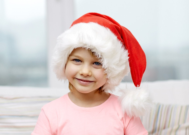 smiling little girl in santa hat at home - 写真・画像