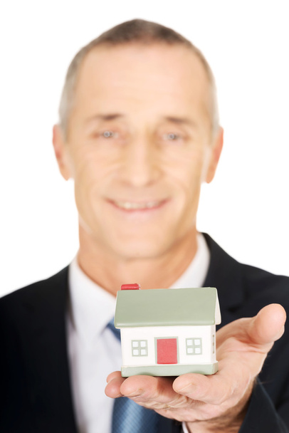 Businessman holding house model - Foto, afbeelding
