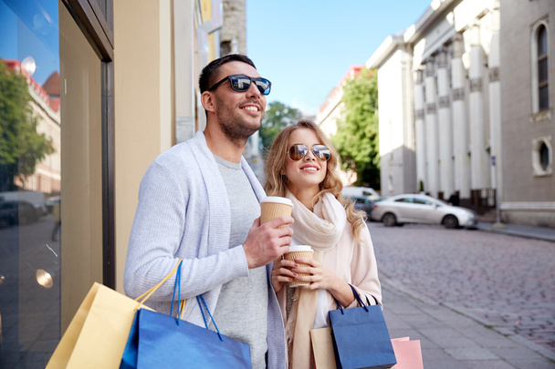 happy couple with shopping bags and coffee in city - Foto, Imagem