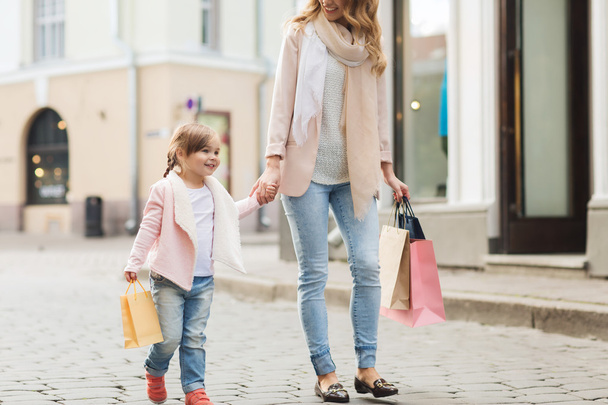 happy mother and child with shopping bags in city - Fotografie, Obrázek