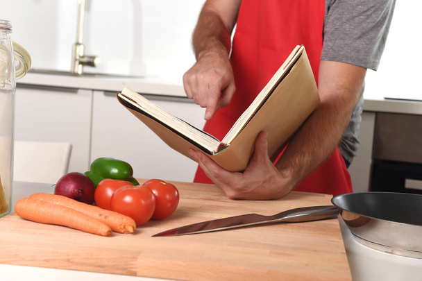 unrecognizable man in apron at kitchen following recipe book hea - Φωτογραφία, εικόνα