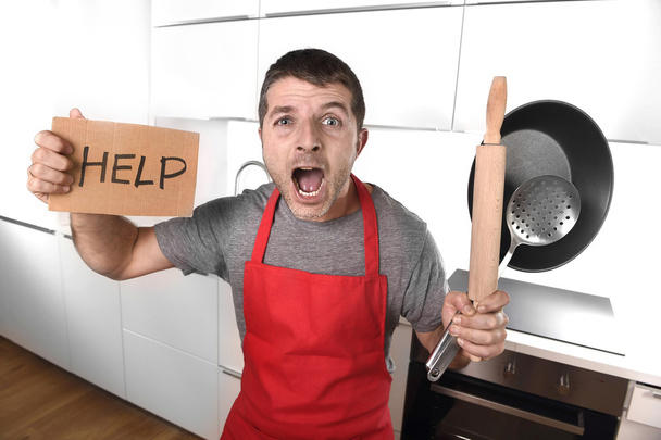 funny scared man holding pan wearing apron at kitchen asking for - Φωτογραφία, εικόνα