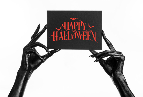 Postcard and Happy Halloween theme: black hand of death holding a paper card with the words Happy Halloween on a white isolated background in studio - Fotó, kép