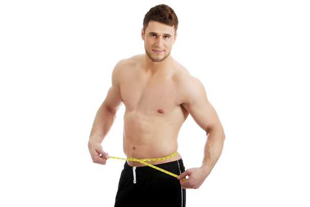 Muscular man measuring his belly. - Foto, afbeelding