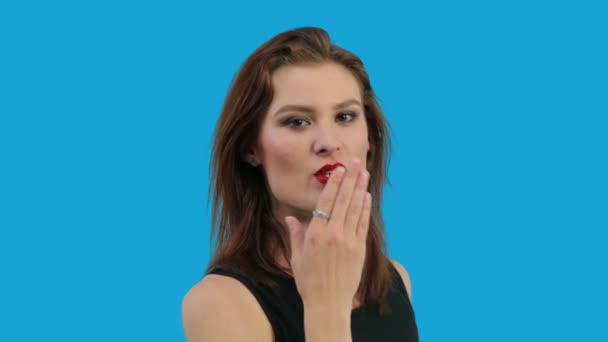 Молода жінка дме поцілунок ізольовані на синьому фоні - Кадри, відео